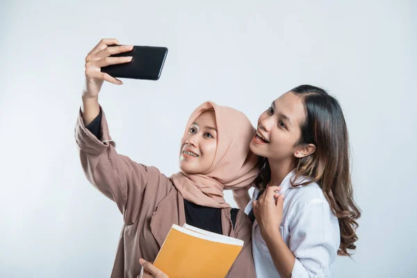 Portret szczęśliwej młodzieży uniwersyteckiej niosącej torbę i robiącej sobie selfie telefonem komórkowym — Zdjęcie stockowe
