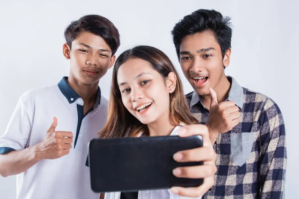 Retrato de jovens universitários felizes carregando um saco e tirando uma selfie com o celular — Fotografia de Stock