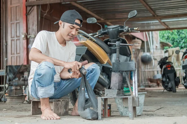 Reifenpatcher sitzt und schrubbt einen undichten Schlauch — Stockfoto