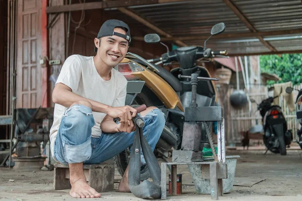 Lächelnder Reifenpatcher sitzt und reibt einen undichten Schlauch — Stockfoto