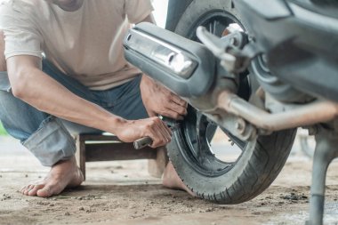 Lastik tamircisi motosiklet lastiklerini sökmek için kazıma aleti kullanıyor.