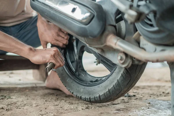 close up the tire repairman hand holding the tire pry tool when removing the motorbike tire