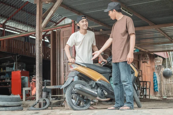 Male customer standing with hand gesture explains to the tire repairman that a motorbike tire has leaked — Stock Photo, Image