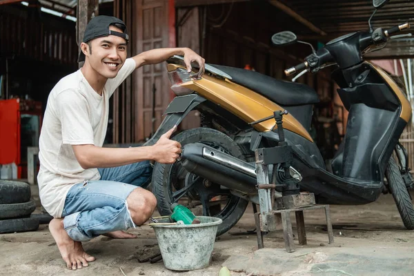 Tire repair shop smiles with thumbs up when finished to repair a damaged motorcycle tire with traditional tools — Stock Photo, Image