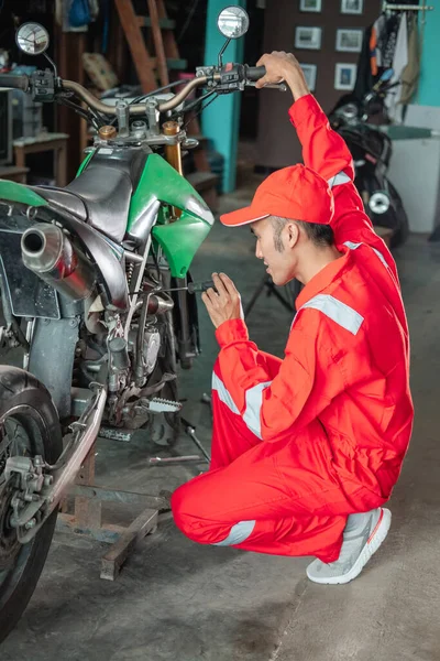 Asiatisk mekaniker ställa in förgasaren med hjälp av en skruvmejsel bredvid dirt bike — Stockfoto