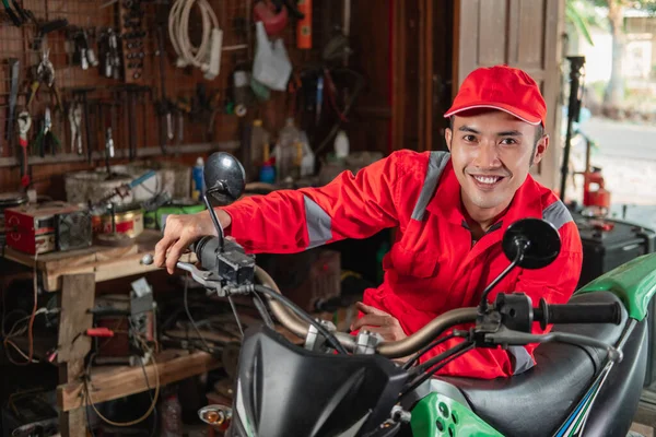 Leende mekaniker i slitstark uniform kontrollera smuts cykel motorer gaspådrag — Stockfoto
