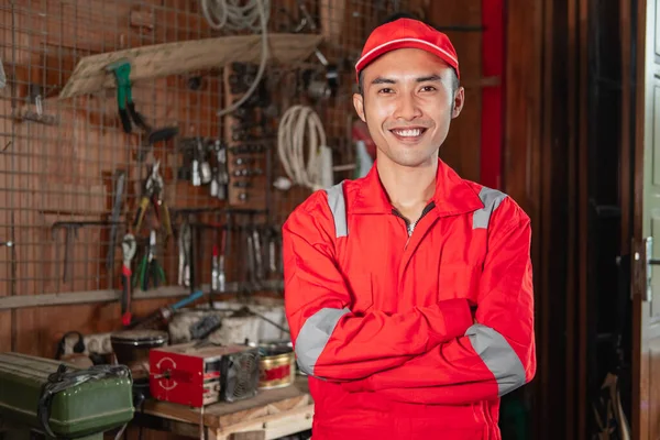 Leende ung mekaniker i slitstark uniform med korsade händer stående — Stockfoto