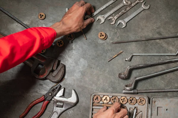 Afbeelding van mechanische handen met verschillende werkplaatsgereedschappen op de vloer — Stockfoto