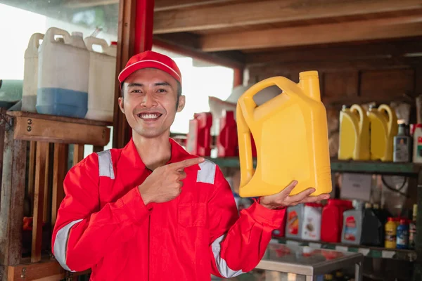Närbild av mekaniker i wearpack och hatt står med fingret pekande medan du bär oljeflaska — Stockfoto