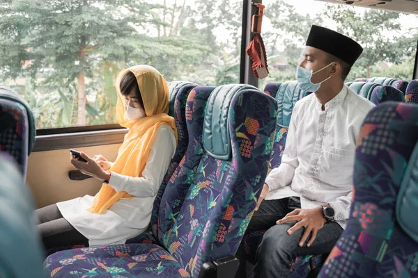 Pasangan muslim memakai topeng perjalanan dengan bus selama hari libur Idul Fitri — Stok Foto