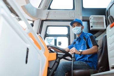 Otobüs şoförü üniforma ve maske giyiyor