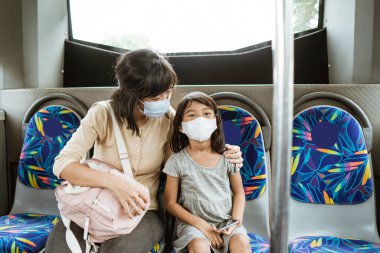Anne ve kızı salgın sırasında toplu taşıma araçlarına biniyorlar.