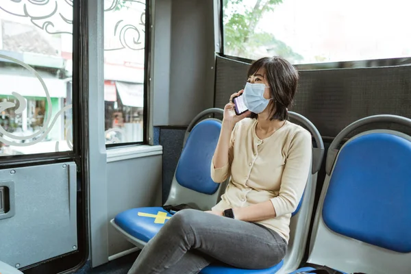 Asian woman riding a public transport wearing face mask — Stock Photo, Image