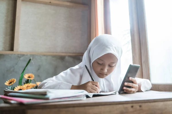 Indonéská školačka studuje domácí úkoly během své online lekce — Stock fotografie
