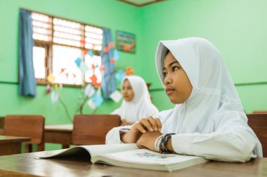 a portrait of an indonesian muslim student watching her teacher teaching