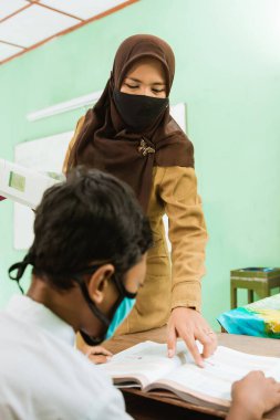 a portrait of Indonesian teacher teaching activities wear a mask