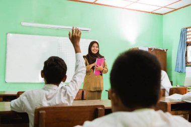 student raising hands in class when teacher teaching