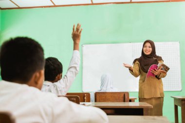 student raising hands in class when teacher teaching