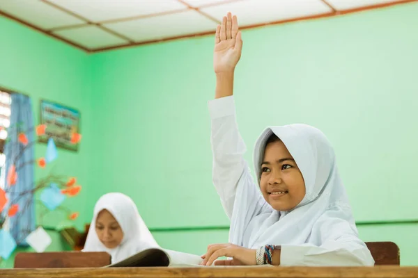 Estudante da escola primária indonésia levantando as mãos na classe — Fotografia de Stock