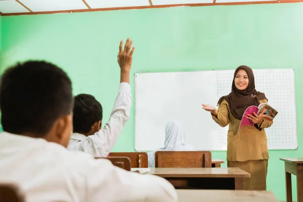 Murid yang mengangkat tangan di kelas ketika guru mengajar — Stok Foto