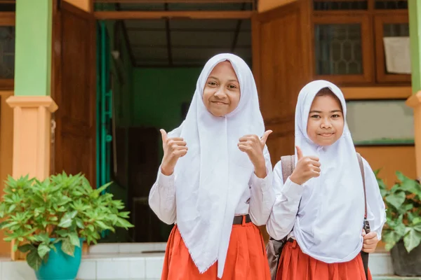 Deux élèves du primaire portant l'uniforme de l'école montrant pouces jusqu'à la caméra — Photo