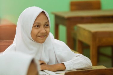 a portrait of an indonesian muslim student watching her teacher teaching