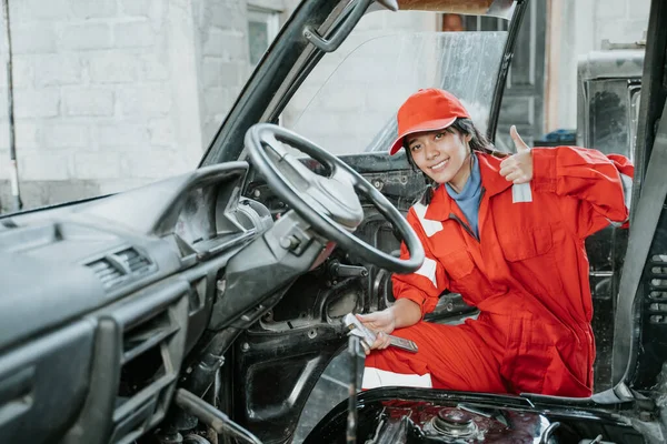 Portrait of a young woman working showing thumbs up as an happy mechanic — Stock Photo, Image