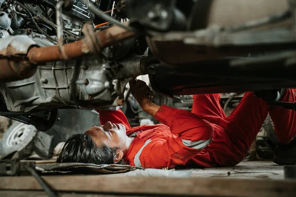 Человек ремонтирует часть сломанного двигателя автомобиля — стоковое фото
