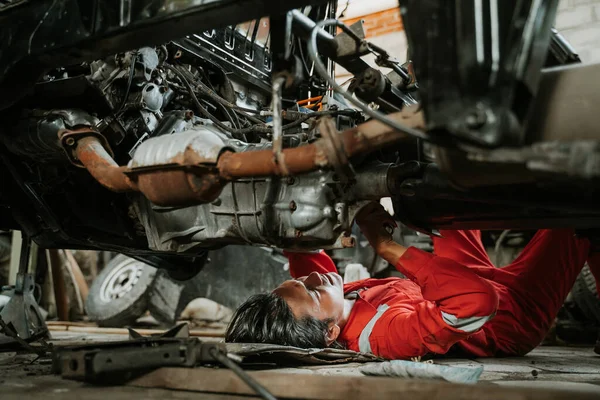 Человек ремонтирует часть сломанного двигателя автомобиля — стоковое фото