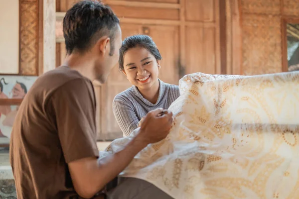 Junge Frau und Mann zeichnen Batik auf ein weißes Tuch — Stockfoto