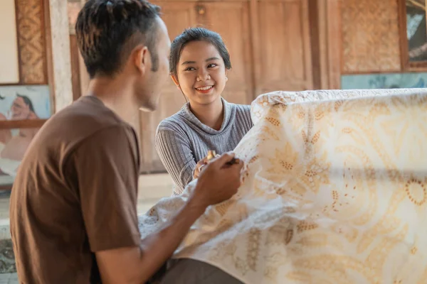 Wanita muda dan pria menggambar batik pada kain putih — Stok Foto