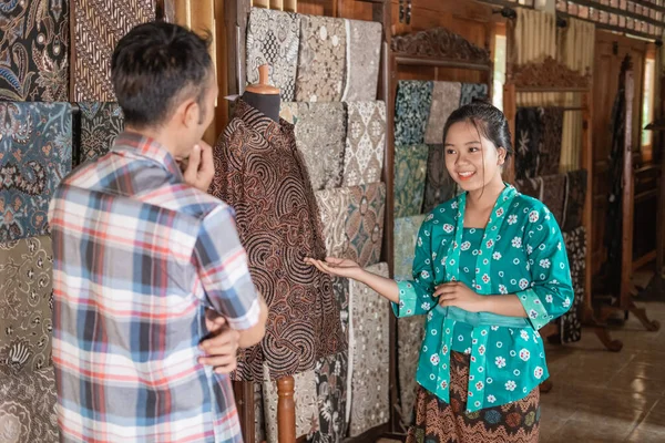 Seorang wanita yang menunjukkan pakaian batik tradisional yang dia jual — Stok Foto