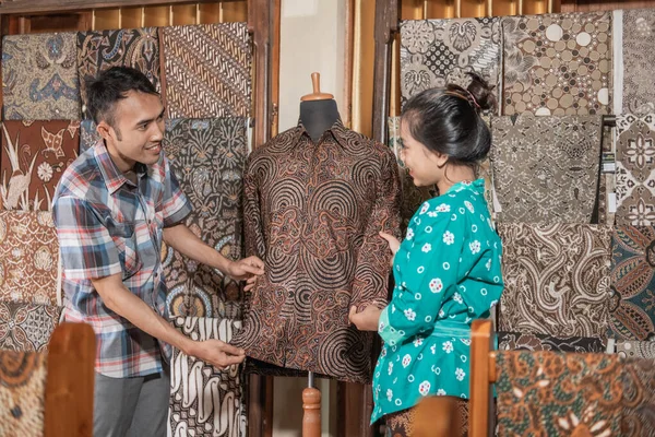 Seorang wanita yang menunjukkan pakaian batik tradisional yang dia jual — Stok Foto