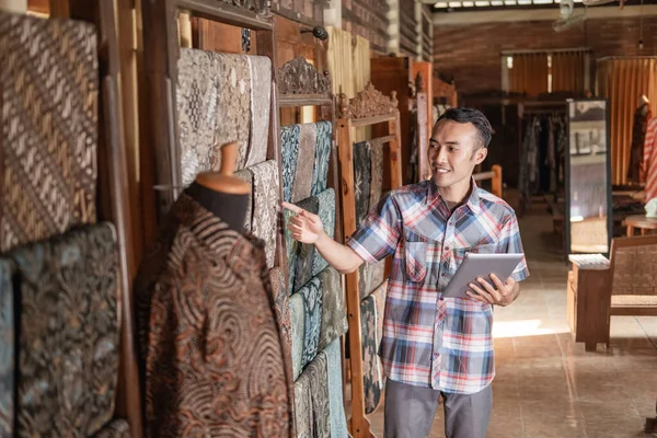 Retrato de homens jovens verificando estoque batik tradicional — Fotografia de Stock