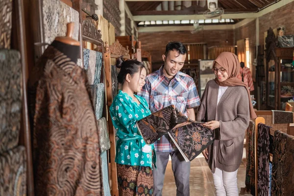Woman showing the traditional batik cloth she sells to customer — ストック写真