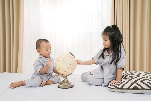 Retrato feliz de um irmão irmã jogando globo — Fotografia de Stock