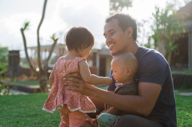 Baba parkta çocuklarına sarılarak oynuyor.