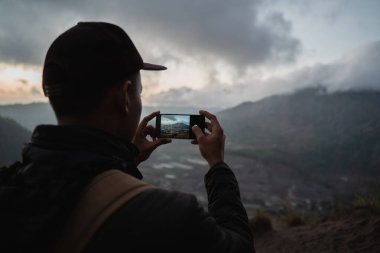 Sırt çantası ve telefonu olan bir fotoğrafçı.