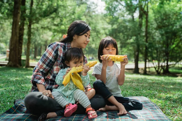 Ritratto di una madre che accompagna suo figlio mangiare mais — Foto Stock