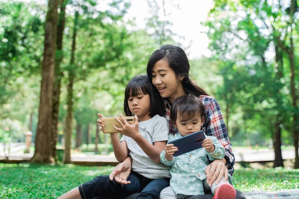 Porträt einer Mutter, die ihr Kind zum Handyspielen begleitet — Stockfoto