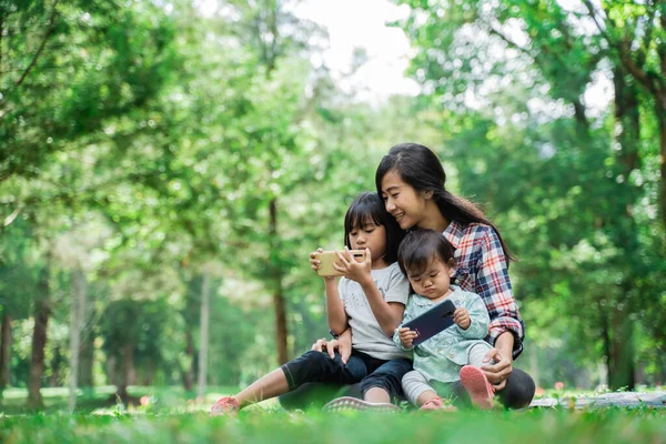 자녀와 함께 핸드폰 놀이를 하는 어머니의 모습 — 스톡 사진