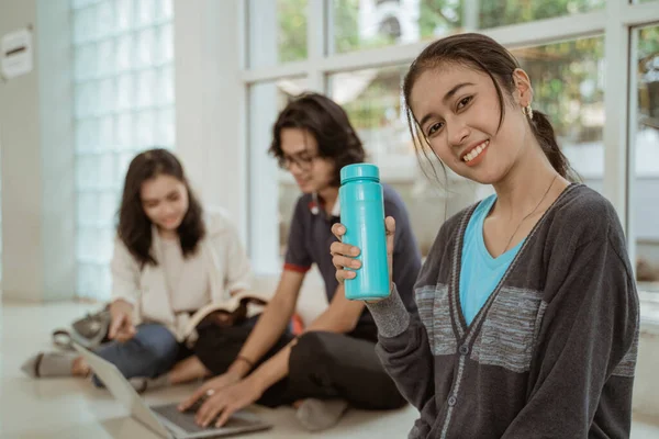 Portré szórakoztató diákok bemutató palackozott víz üljön le csoportokban — Stock Fotó