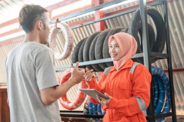 Peçeli kadın tamirciler ayakta duran erkek tüketicilerle sohbet ederken dijital tabletler kullanıyorlar