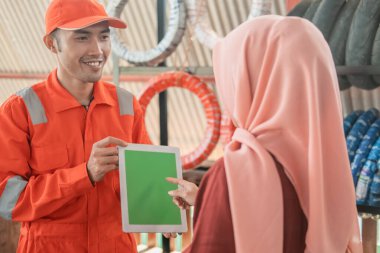 Bir müşteriyle dijital tablet takan giysili bir tamirci.