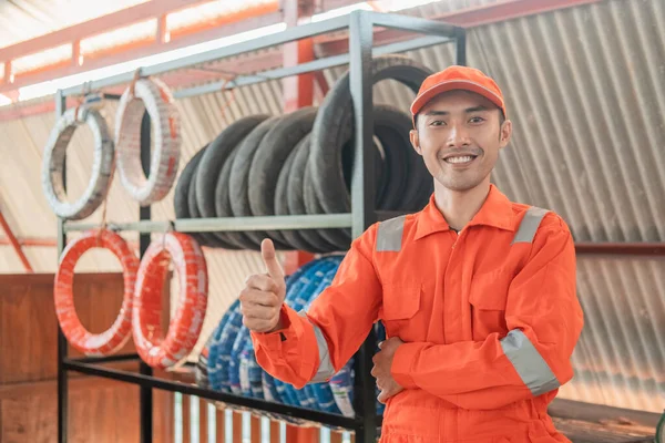 Mecánico en wearpack rojo con pulgares hacia arriba mientras que en el taller —  Fotos de Stock