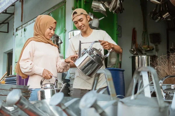 Asian male merchant showing off traditional kettles to veiled women — Stock Photo, Image