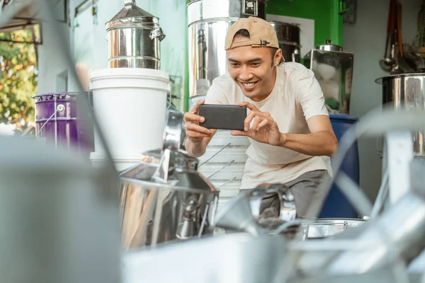 Lächelnder männlicher Verkäufer mit Handykamera beim Fotografieren einer Ware für den Online-Shop — Stockfoto