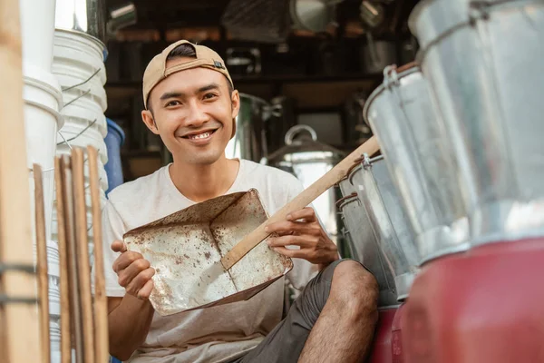 Lächelnder Handwerker mit einem Mülleimer in der Hand, wenn er vor die Kamera tritt — Stockfoto