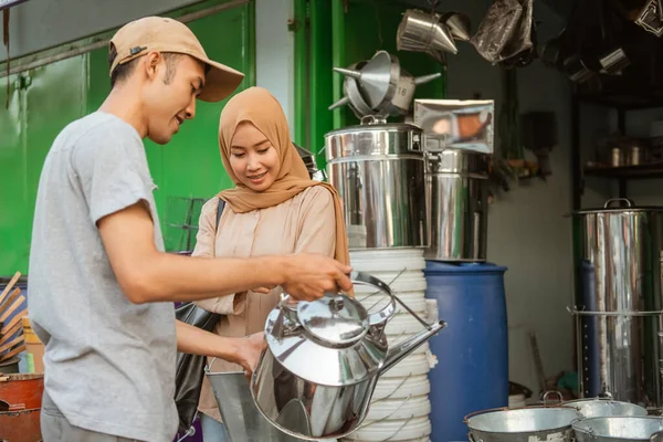 Vendedor masculino segurando a chaleira quando servir mulher compradores à procura de bens — Fotografia de Stock