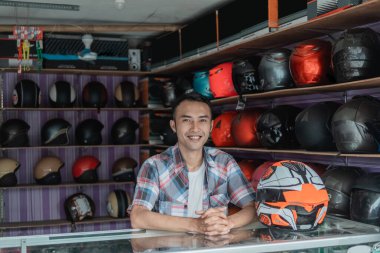 Kask satıcısı elleri kask dükkanının vitrinlerinde dinleniyor.